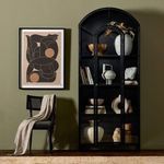 Black metal cabinet in olive green room styled with black chair, throw blanket, and framed abstract art