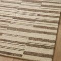 Angled upper corner detail of rug showing plush pile and color contrast on wood floor.