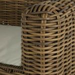 Close-up detail of rounded armrest corner with natural brown rattan wicker and white seat cushion edge