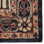 Side view of rug in room with wooden chair and braided pouf with dark blue base