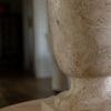 Side close-up showing aged travertine texture and natural veining on lamp base in indoor setting