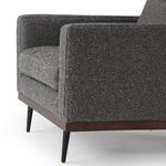 Side-front angle displaying armrest shape and almond wood base continuity
