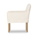 Side profile of Addington armchair highlighting smooth linen upholstery and wooden legs