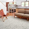 Hagen rug styled in a modern living room under a brown sofa and leather chair on wood floor