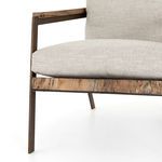 Partial view of plush light fabric cushion meeting wood armrest