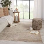 Rug styled in living room with beige sofa, throw pillows, round ottoman, and accessories near large window