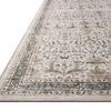 Close-up side angle showing low pile texture and detailed outer border of ivory and stone traditional rug