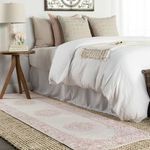 side view of bed area with runner rug, neutral bedding, wooden side table, and table lamp