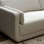 Close-up of left armrest and loose arm cushion with wood floor visible beneath sectional