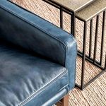 Overhead view displaying navy leather chair armrest near side table on textured carpet