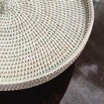 Close-up on textured rattan weave and glass insert edge on dark wood surface