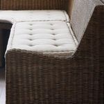 Front corner angle showing lower open shelf under seating with woven rattan frame