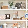 Bond lamp displayed on lower shelf among varied decorative home items including pillows and ceramics
