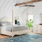 Bed shown in styled bedroom with vaulted ceiling, wooden beams, blue rug, and light-colored furniture