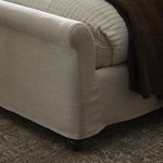 Partial close-up of headboard top corner highlights fine stitching on cream linen slipcover