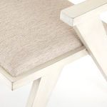 Close-up of textured beige fabric upholstery on seat alongside cream wood frame