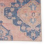 Focused detail of blue medallion edge with subtle floral motifs on pink distressed background