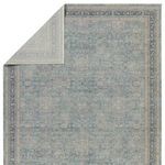 Rug flipped to show backside with muted version of blue and taupe traditional pattern and lightweight weave.
