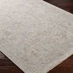 Side angle showing textured edges and detailed weave of the light gray rug on dark hardwood floor