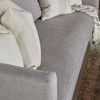 Sofa with additional beige and cream pillows and throw blanket, angled view
