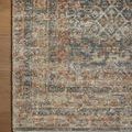 Macro shot of rug corner showing densely detailed vintage pattern and faded blue and rust hues