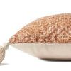 Side view showing pillow thickness with textured orange fabric on top and plain cream fabric bottom with tassel detail