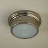 Flush mount light installed on ceiling viewed slightly from below showing polished metal rim and white shade