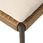 Close-up on corner showing beige cushion fabric texture and wicker wrapped frame corner