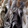 Rolled linen napkins in multiple colors with twine and dried grass on wooden surface