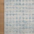 Top corner view highlighting subtle diamond and checkerboard patterns on Kamala Sky Dove rug on wooden floor