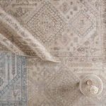 Rug placed in styled room setting with neutral decor and round woven container on top