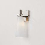 Side angle of Trude Wall Sconce showing lit opal shade and sleek metal arm detail