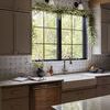 Large daisy stoneware planter placed in a kitchen sink corner with grey cabinets and leafy window decor