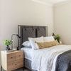 Nightstand styled next to bed with lamp, books, and greenery in bright bedroom setting