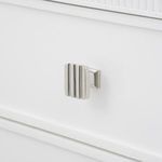Polished nickel pull with vertical ridges mounted on white drawer front of Sienna table base
