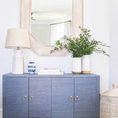 Meredith cabinet styled in a bright room with mirror, lamp, plants, and decorative accessories