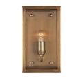 Front-facing view of sconce with lit filament bulb inside rectangular glass and brass frame