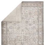 Odel rug folded to reveal solid light gray backing and front faded traditional floral pattern