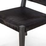 Close-up of Villa Dining Chair seat upholstery, highlighting black hair on hide texture and wooden legs