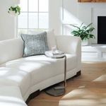 Close-up of sectional corner with aqua accent pillow and small metal side table in bright room