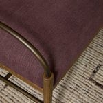 Side corner close-up highlighting metal arm and amber ash leg on woven rug