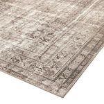 Angled view of rug corner showing low pile and faded border with floral elements