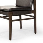 Close-up of chair frame corner highlighting leather upholstery and wood grain detail