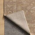 Louisa rug corner turned up to reveal a gray non-slip rug pad underneath
