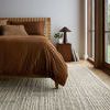 Low angle shot of Tallulah Mist Ivory Rug under bed near large windows showing rug’s scale in room