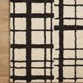Corner of Polly Black Ivory Rug on light wood floor emphasizing high contrast lines and plush pile