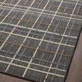Close-up on textured charcoal plaid rug laying flat on dark wood floor