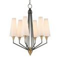 Chandelier lit with warm light showing eight white conical shades and bronze frame from front