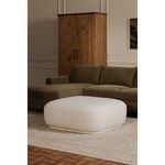Marion Square Ottoman in room setting in front of green sectional sofa and wooden cabinet