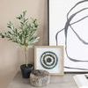 Close-up of Black Circles IV painting corner with nearby potted plant and textured decorative objects on console